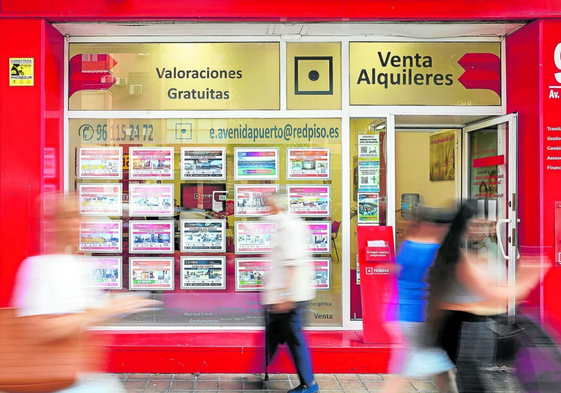 Varias personas caminan junto a la puerta de una inmobiliaria de Valencia, en una imagen de archivo.