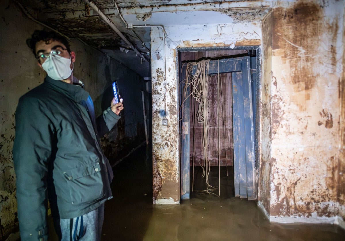 Imagen principal - Carlos junto al ascensor destrozado, un carro flota sobre aguas fecales en el segundo sótano de la finca y un voluntario del Grupo Balear de Rescate comprueba el estado de los pilares.