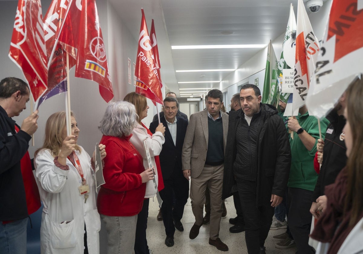 Mazón, este martes en el Clínico rodeado de manifestantes sindicales.