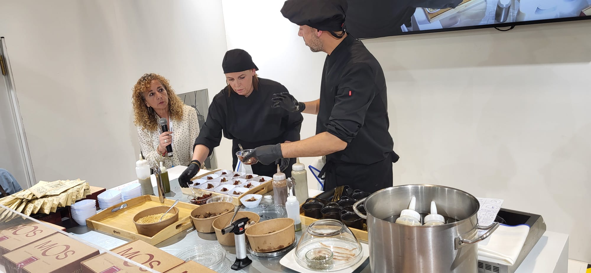 Imagen principal - Arriba, momento de la elaboración de la coca de fira. Sobre estas líneas, las autoridades reciben el cofre de la marca MOS y otro momento de la demostración gastronómica.