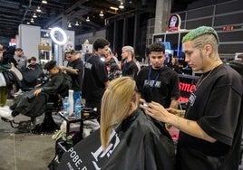 Un barbero realiza un corte de pelo durante la feria.