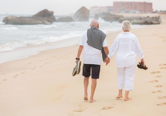 Dos jubilados paseando por la playa.