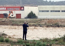 Un hombre fotografía el barranco del Poyo a su paso por Riba-roja en la tarde del 29 de octubre.