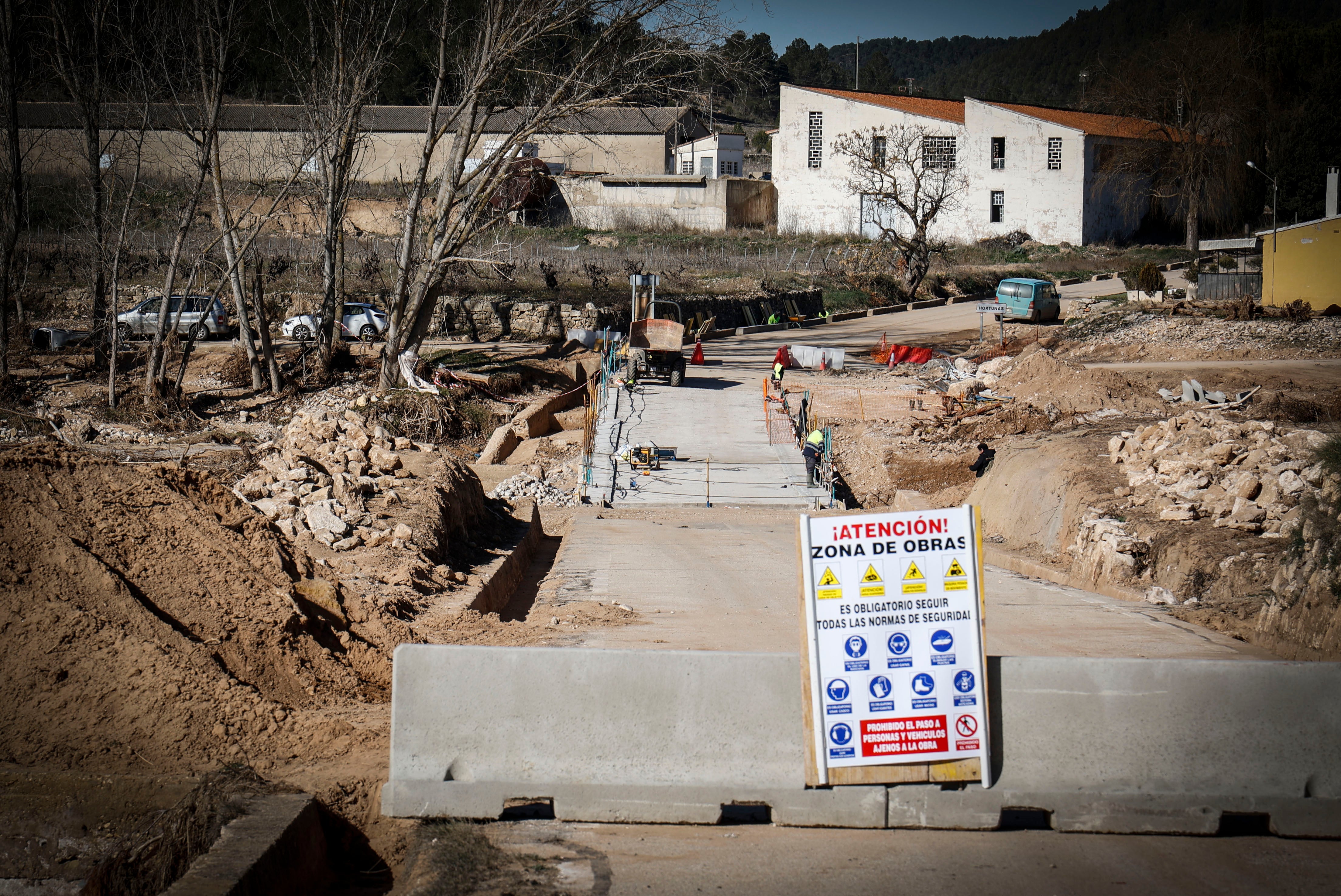 Imagen secundaria 2 - José trabaja en su casa entre el barro y los destrozos. La furia del Magro destrozó el cauce y las casas cercanas de la aldea. La carretera, aún cortada, con obreros reparando el puente derribado.