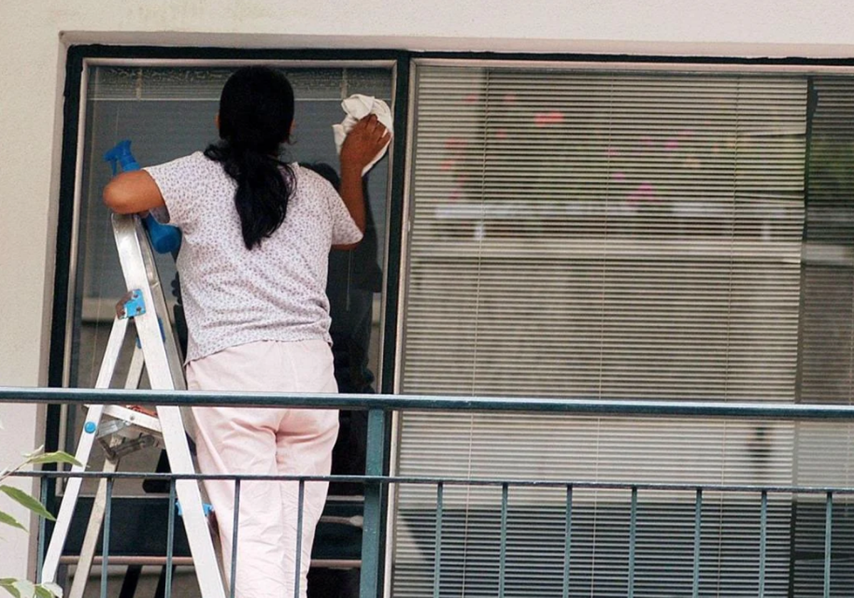 Una trabajadora limpia una ventana.