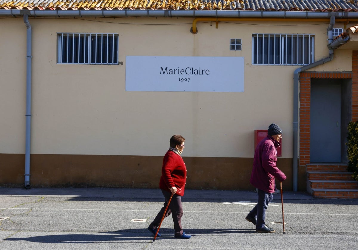 Dos ancianos pasean por el desangelado acceso de la fábrica con más de cien años de historia.