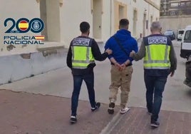 Dos agentes de la Policía Nacional conducen a uno de los detenidos