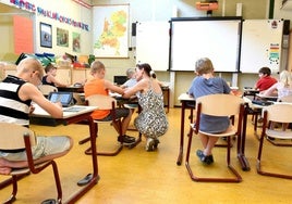 Una maestra atiende a un niño sentado en una aula de Primaria.