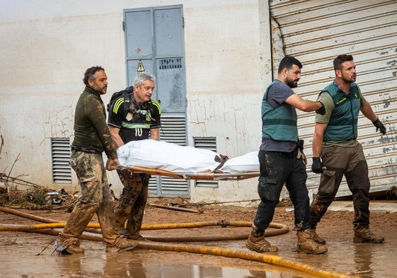 Dos guardia civles y dos voluntarios trasladan un cuerpo en Catarroja.