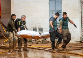 Guardias civiles y personal de limpieza ayuda en el traslado de un cadáver.