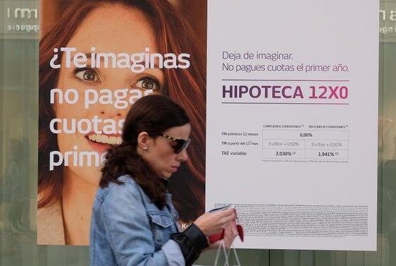 Una mujer camina junto a un escaparate con un anuncio de hipotecas, en una imagen de archivo.