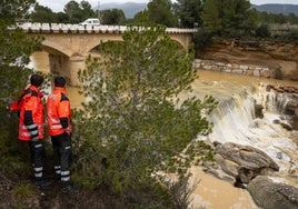 Dos bomberos vigilan el cauce del río.