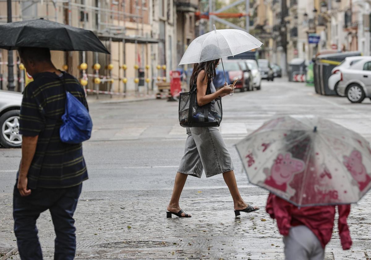 Vecinos de la ciudad de Valencia transitan por el centro bajo el temporal de lluvias.