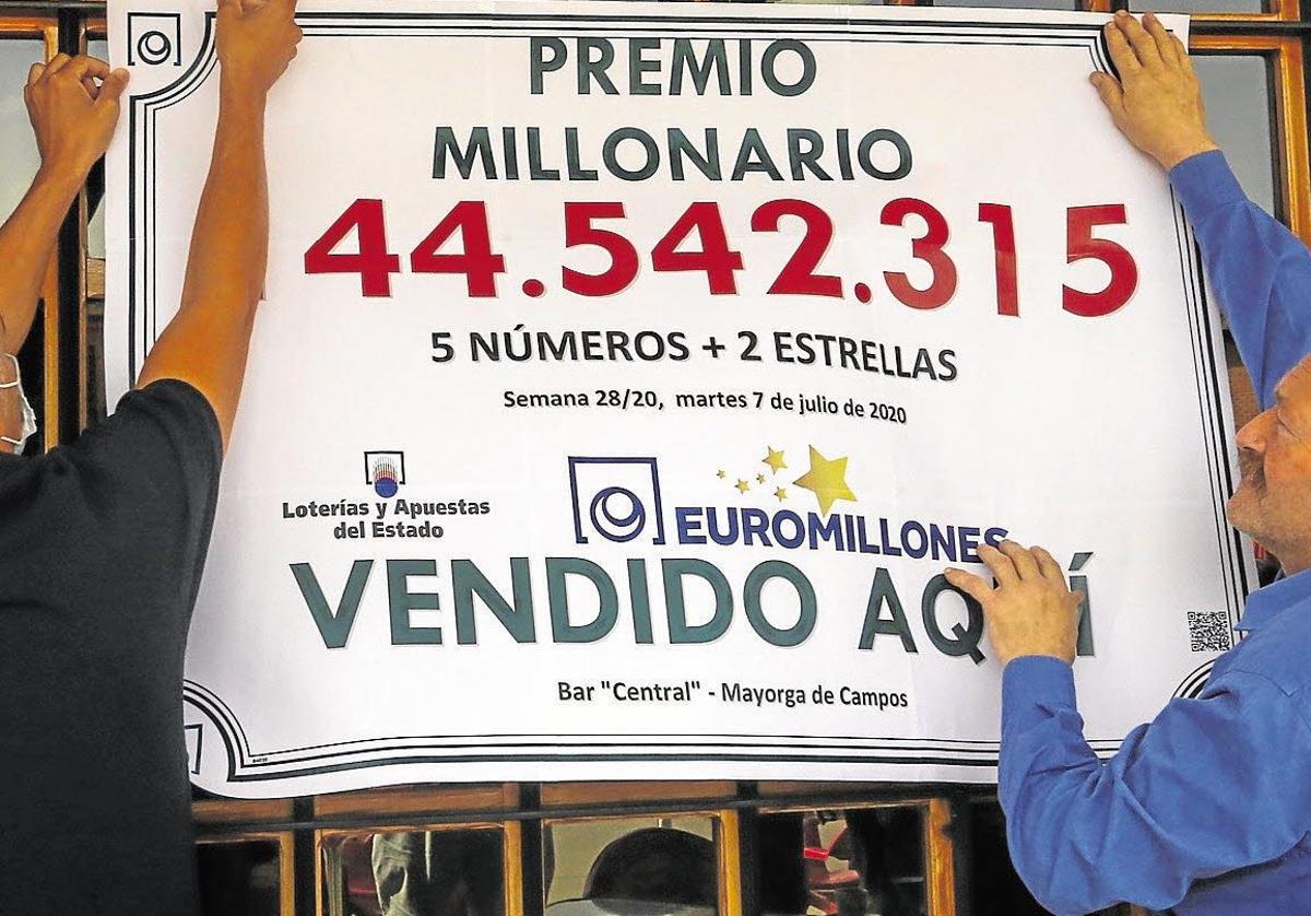 Dos de los afortunados ganadores del Euromillón cuelgan el cartel con el premio obtenido. Imagen de archivo.