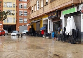 Calle de Paiporta con la terraza de un bar recogida por la lluvia.