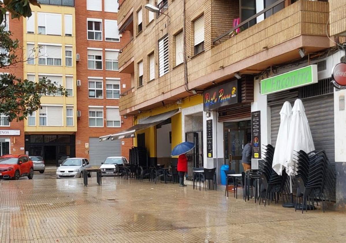 Calle de Paiporta con la terraza de un bar recogida por la lluvia.