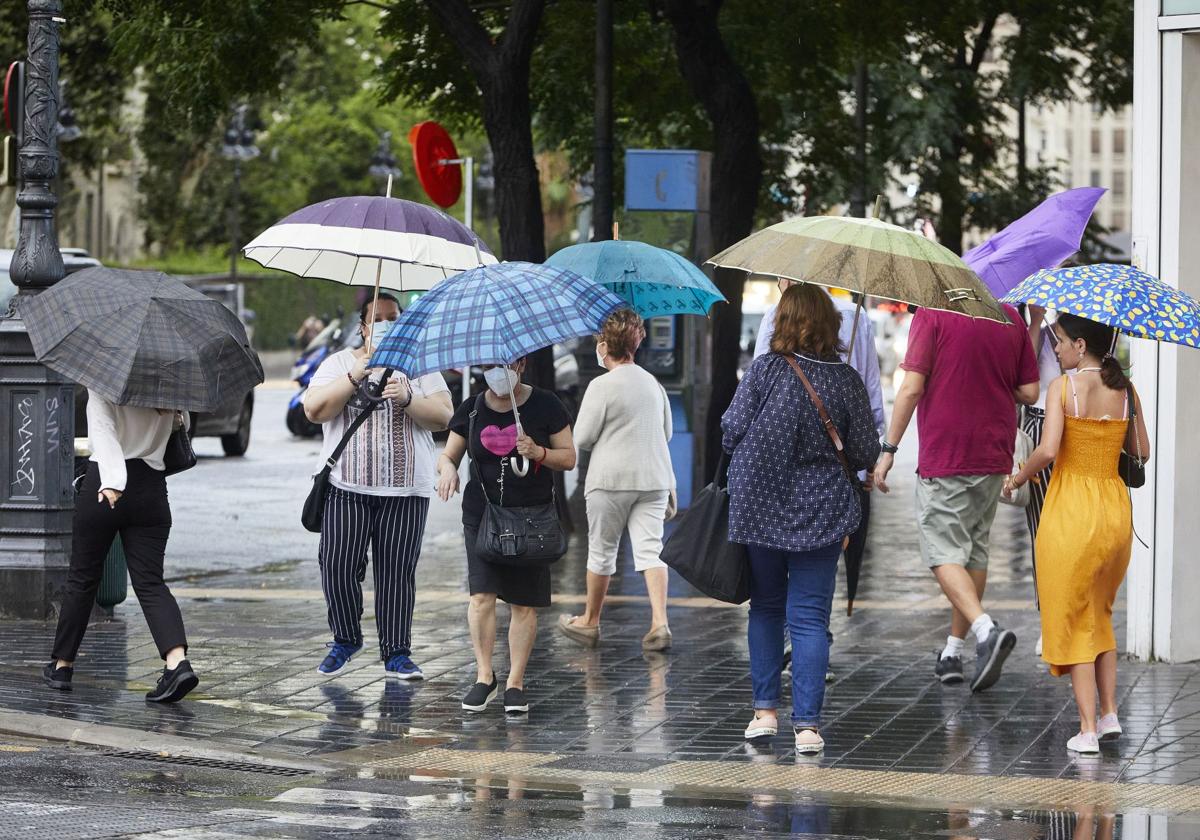 Varios ciudadanos pasean bajo la lluvia. Imagen de archivo.