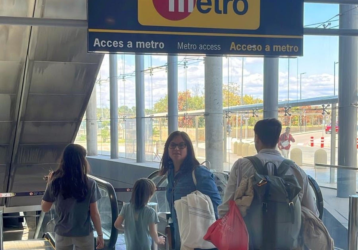 Una familia, a las puertas de los accesos del aeropuerto al metro en dirección a Valencia, cerrado.
