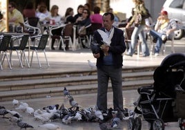 Un hombre dando de comer a las palomas en una imagen de archivo.