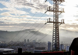Una persona observa el cableado con el que red eléctrica transporta la energía sobre la ciudad de Bilbao.
