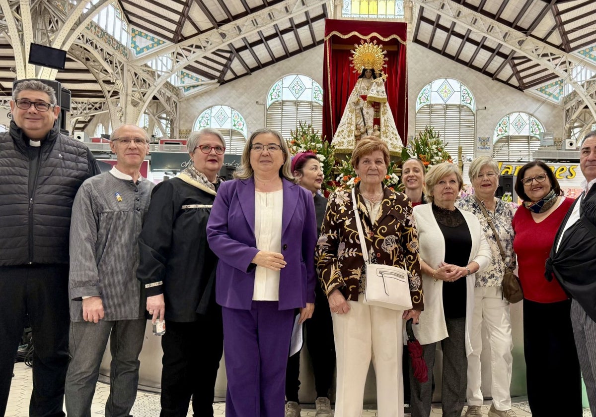 Imagen principal - Cantos a la Mare de Déu y posado de los asistentes al acto en el Mercado Central de Valencia.