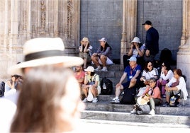 Un grupo de turistas descansa y come algo en los escalones de la Lonja, esta semana.