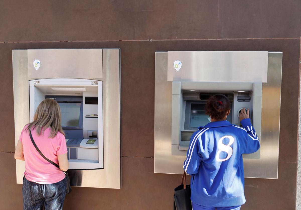 Dos mujeres retiran dinero de un cajero automático.