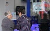 Administración de lotería junto al cartel de un premio millonario.