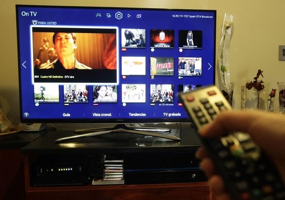 Un hombre sintoniza los canales de su televisor.