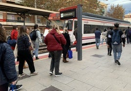 Unos viajeros se dirigen a un tren de cercanías.