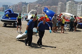 Dos operarios de una funeraria retiran el cuerpo de un fallecido por ahogamiento en la playa de Cullera, en una foto de archivo.