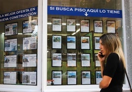 Una mujer pasa frente al escaparate de una inmobiliaria.
