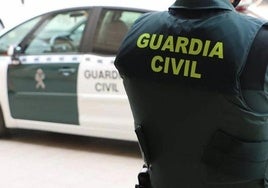 Agente de la Guardia Civil junto a un coche oficial