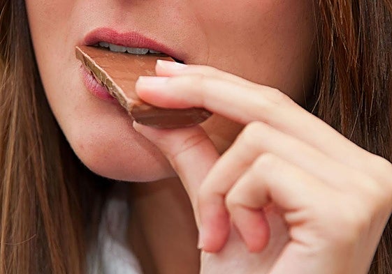 Una mujer se come una galleta de chocolate.