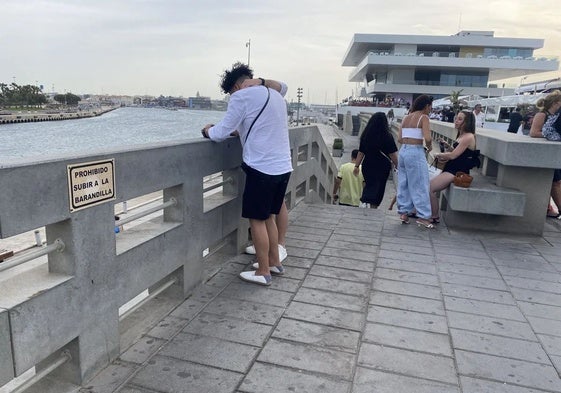 Carteles informativos que advierten de que no se permite sentarse en el muro, en la Marina.