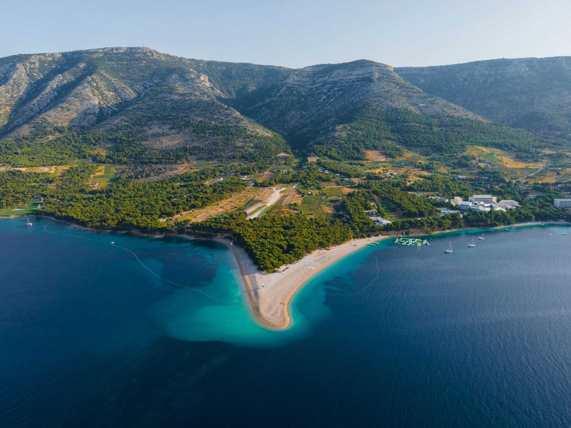 Zlatni Rat, Isla de Brač (Croacia). La describen como una «singular playa en forma de punta de lanza que se extiende como un cuerno dorado en el mar de casi mil metros de largo, acaricia el mar cristalino y turquesa y su extremo cambia de forma en un juego entre el viento, las olas y las corrientes marinas». «Se la considera como una de las mejores playas de Europa y del mundo y es un símbolo del turismo croata y de la belleza natural», añaden. También cuentan que «hay un bosque centenario de pino mediterráneo justo al borde del agua, donde encontrar fácilmente una sombra para escapar del sol durante las horas más calurosas del día». Además, los expertos desvelan que su belleza y popularidad hacen que sea una playa bastante concurrida, pero existen otras calas a lo largo de la costa de Brac mucho más tranquilas. Zlatni Rat es una reserva natural protegida y un destino codiciado tanto para los practicantes de kitesurf como para los surfistas.