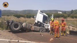 Los bomberos junto al vehículo que se ha salido de la vía.
