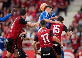 El defensa del Oviedo cabecea el balón ante dos futbolistas del Mirandés.