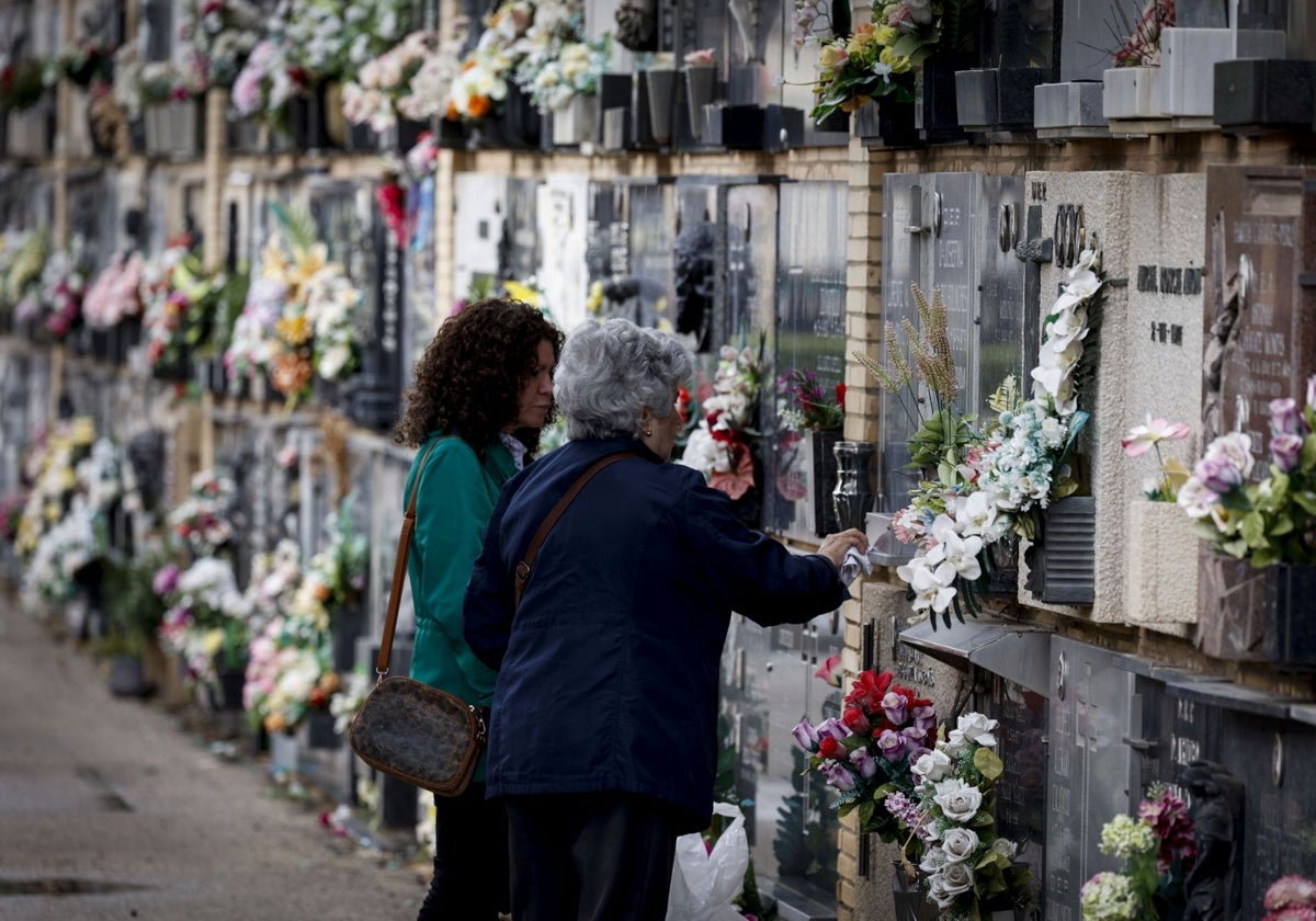 Dos mujeres depositan flores en un lecho del Cementerio General de Valencia.