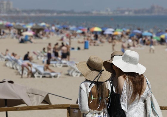 Tres jóvenes observan la playa de la Malvarrosa en Valencia.