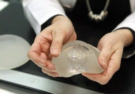 Una doctora manipula una protesis mamaria.