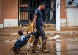 Una familia camina por una calle de Catarroja enfangada tras la dana.