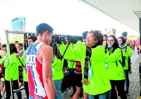 Voluntarios ponen las medallas de finishers a los corredores.