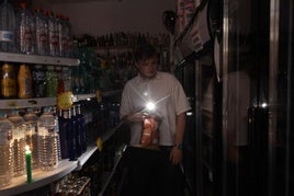 Un hombre se alumbra con la linterna del móvil en un supermercado, el día del apagón.
