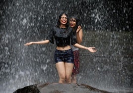 Dos jóvenes se bañan en una cascada.