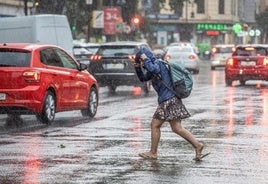 Una chica se intenta refugiar de la lluvia.
