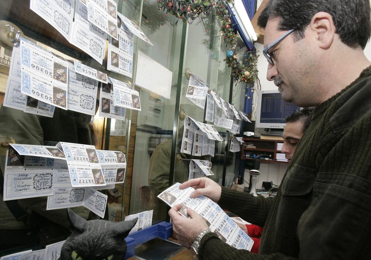 Varias personas compran décimos de lotería de Navidad en una administración de loterías.