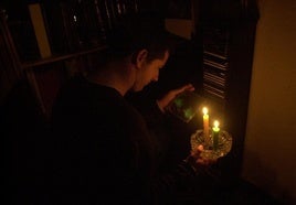 Un hombre se alumbra con unas velas.