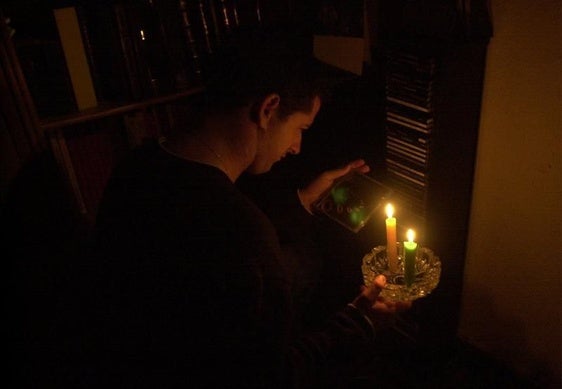 Un hombre se alumbra con unas velas.