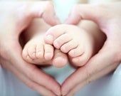 Manos en forma de corazón sosteniendo los pies de su hijo